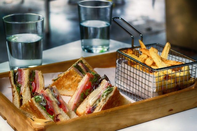 a sandwich with a basket of fries next to it on a wooden tray